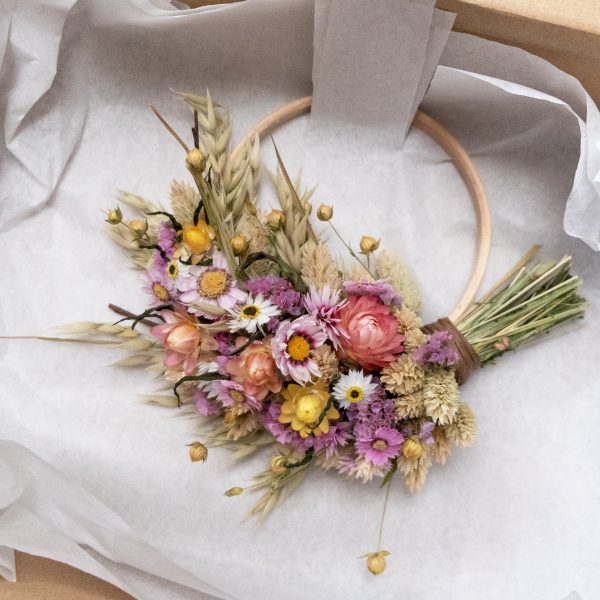 a kraft coloured box with white tissue wrapping. Fixed in the box is a pink and yellow half dried flower wreath