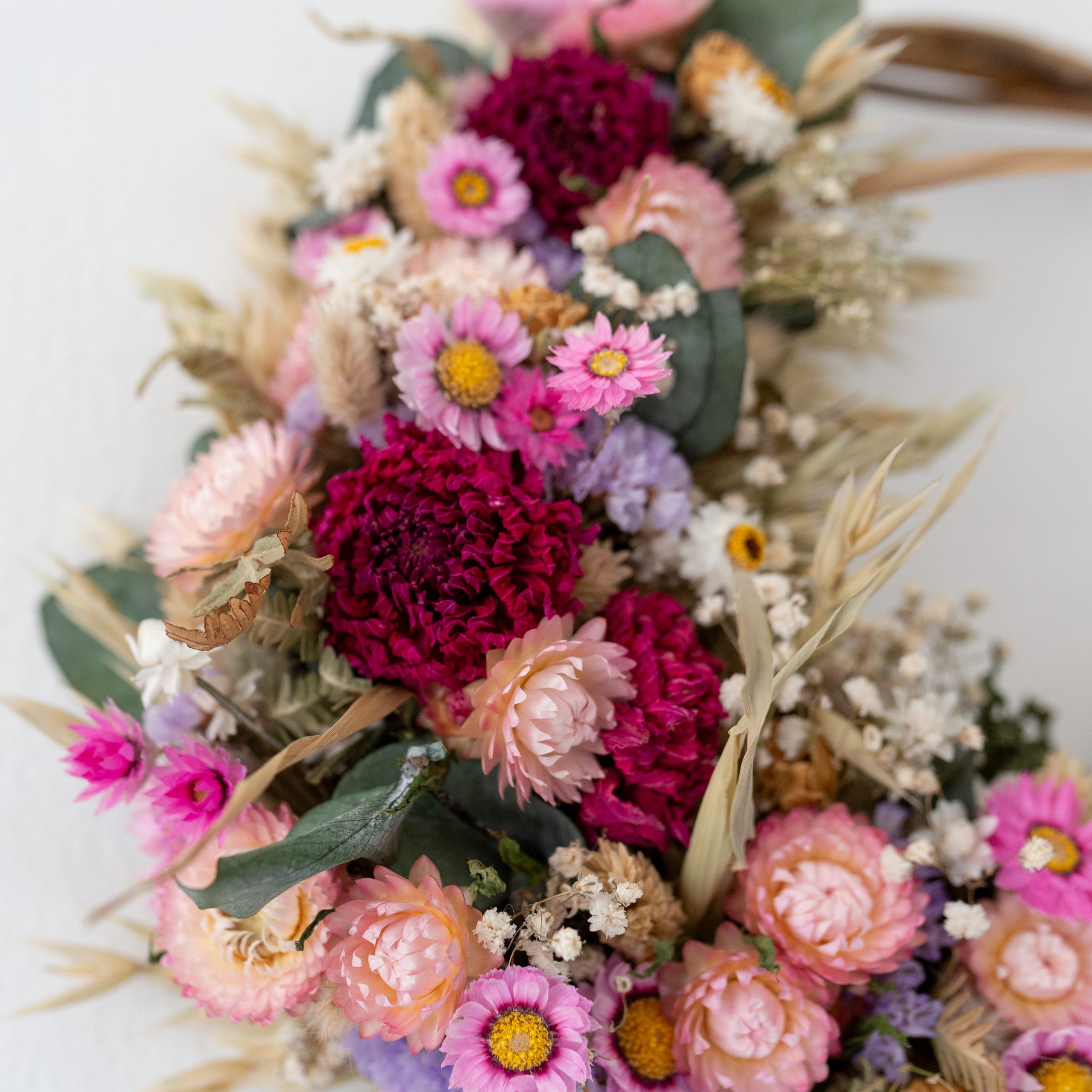 close up of pink dahlias and pale pink strawflowers on a dried flower wreath